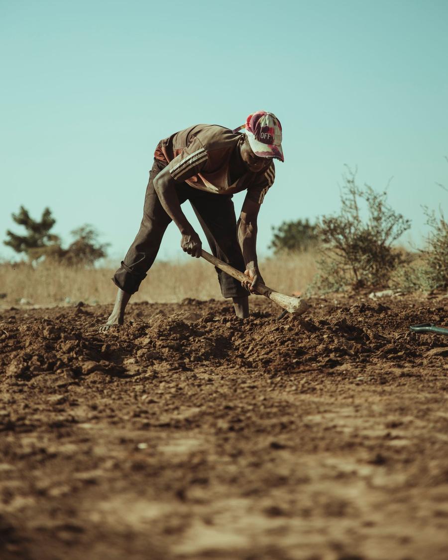 Young farmer preparing land with a hoe