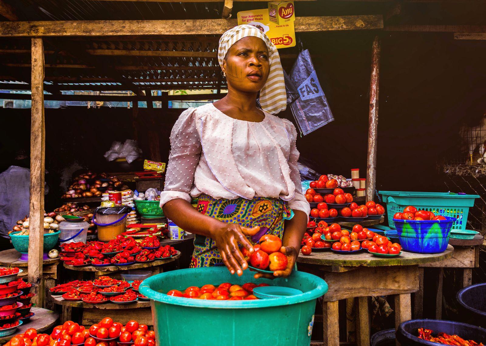 Woman trader selling fresh tomatoes at an open-air market