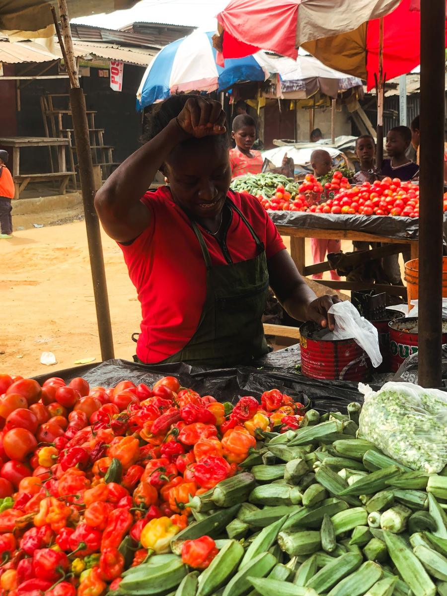 Vendor selling peppers and okra at a vegetable market